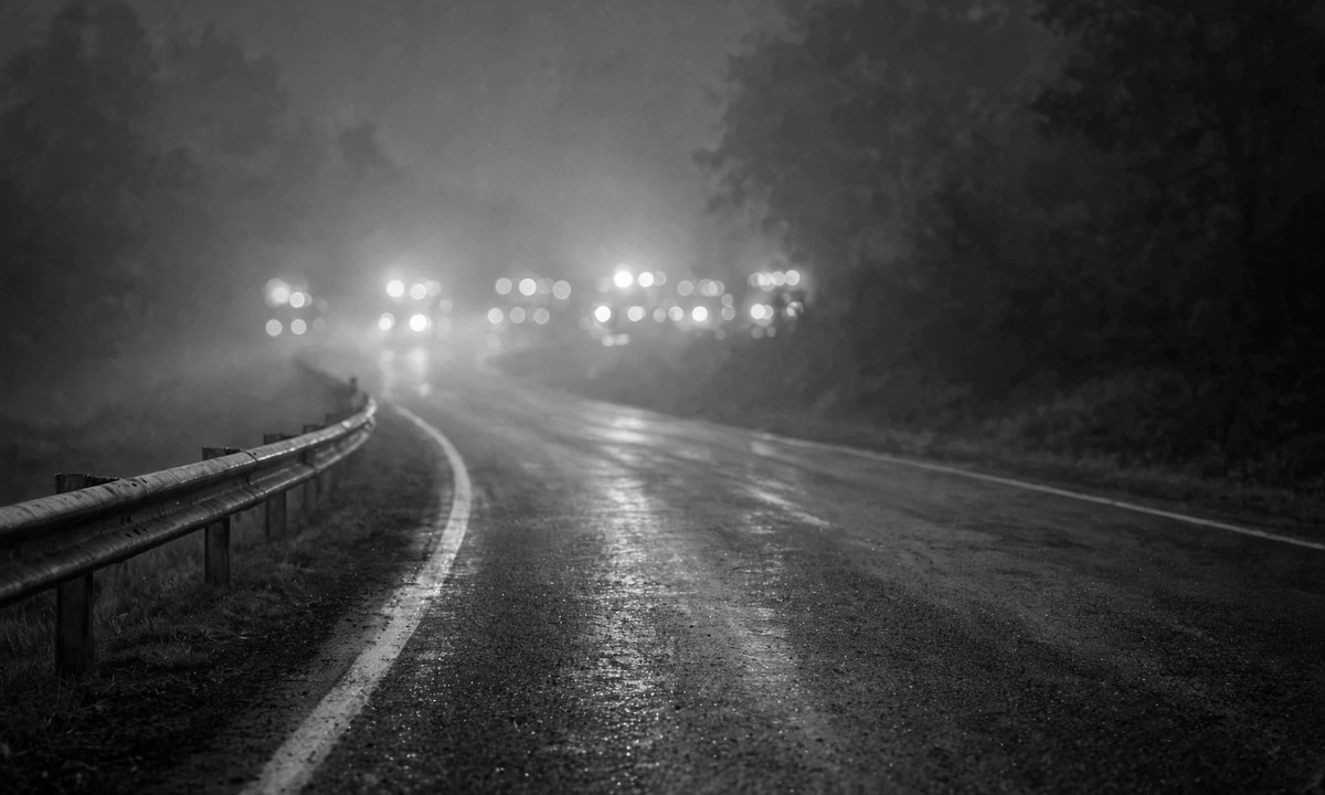 Black and white night highway scene with blurred emergency lights
